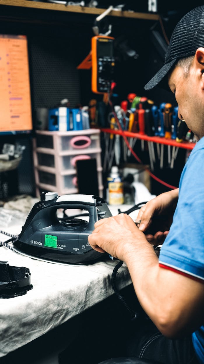 why-choose-us Technician in workshop repairing an electric iron with tools and equipment in the background.